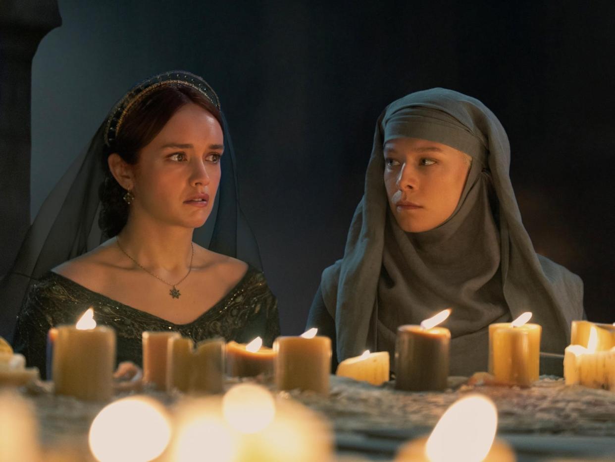 Olivia Cooke as Alicent and Emma D'Arcy as Rhaenyra in front of multiple candles in a dark room.