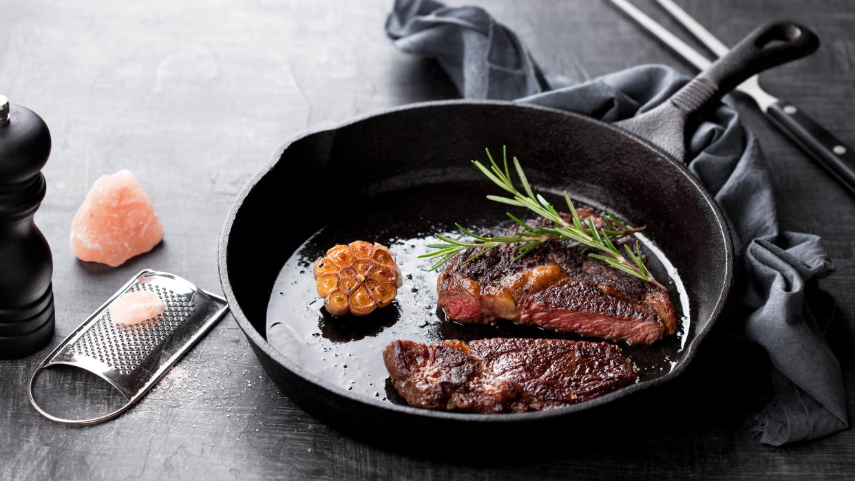  A cast iron skillet cooking steak. 