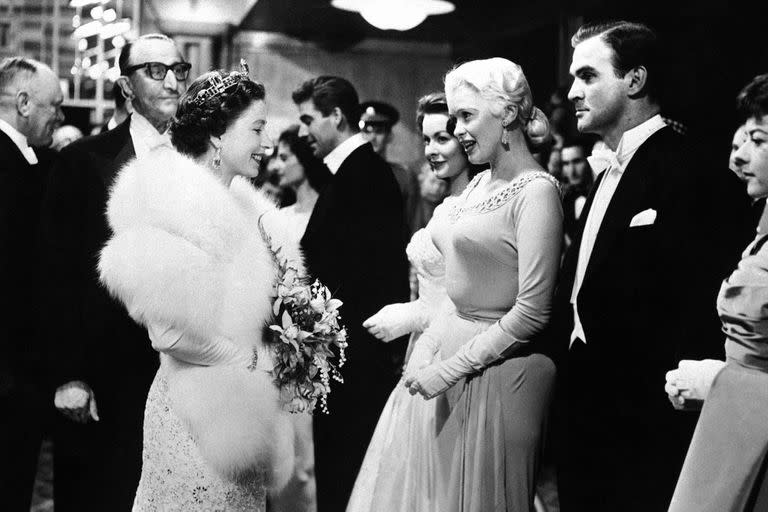 La reina Isabel II con la actriz estadounidense Jayne Mansfield y el actor británico Stanley Baker, durante un festival anual de cine real en el Teatro Odeon de Londres, el 4 de noviembre de 1957