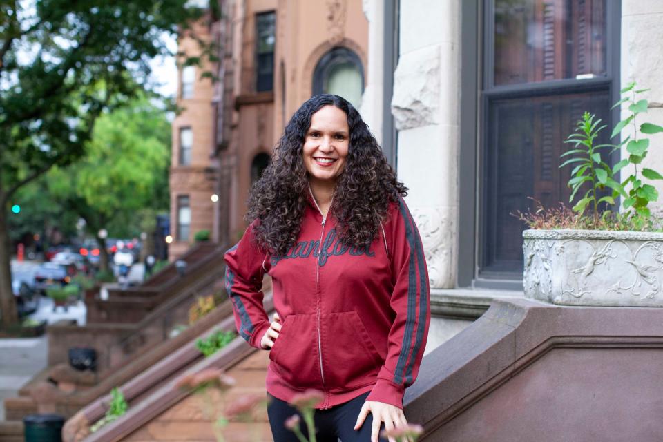 a woman with curly hair stands in a red jacket