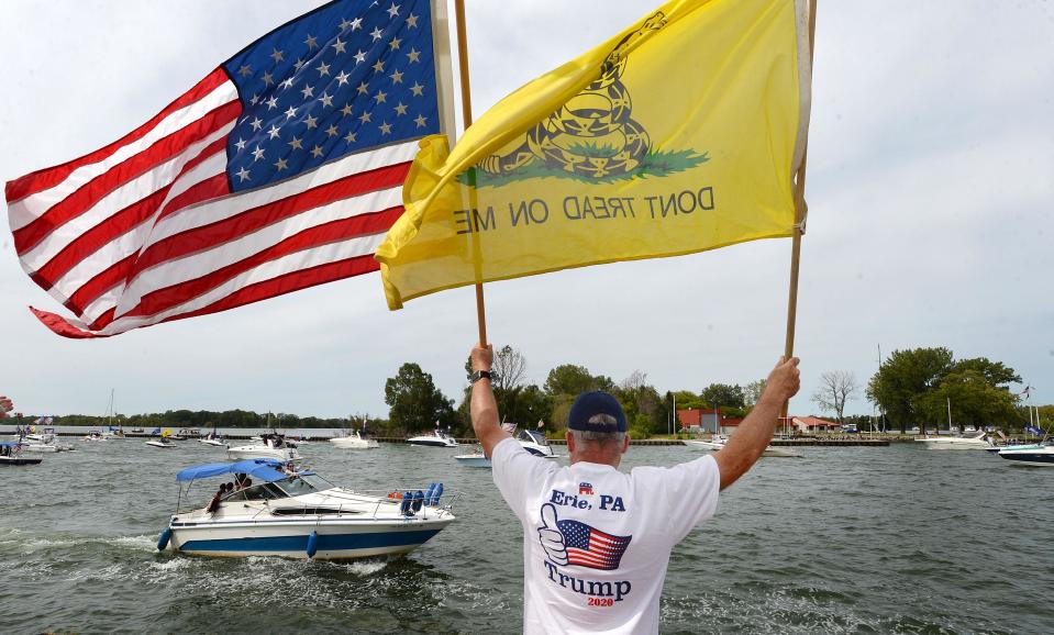 Roger Scarlett of Edinboro greets boaters on the South Pier in Erie during a boat parade in support of President Donald Trump on Sunday. The parade started at the Presque Isle Lighthouse and ended at Dobbins Landing.