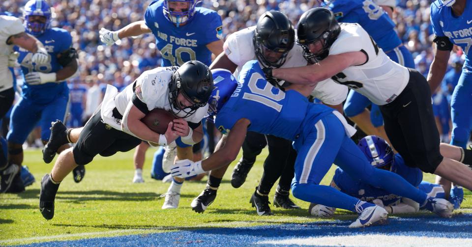 Army quarterback Bryson Daily (13) dives into the end zone for a touchdown as Air Force safety Jayden Goodwin (16) comes in for the tackle in the first half of a game Saturday, Nov. 4, 2023, in Denver. (AP Photo/David Zalubowski)