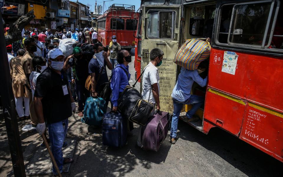 Migrant workers queue for a bus to take them to the train that will transport them home from Mumbai - EPA