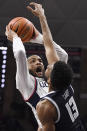 Connecticut's Tyrese Martin, left, reacts as he is fouled by Georgetown's Donald Carey (13) in the first half of an NCAA college basketball game, Tuesday, Jan. 25, 2022, in Storrs, Conn. (AP Photo/Jessica Hill)