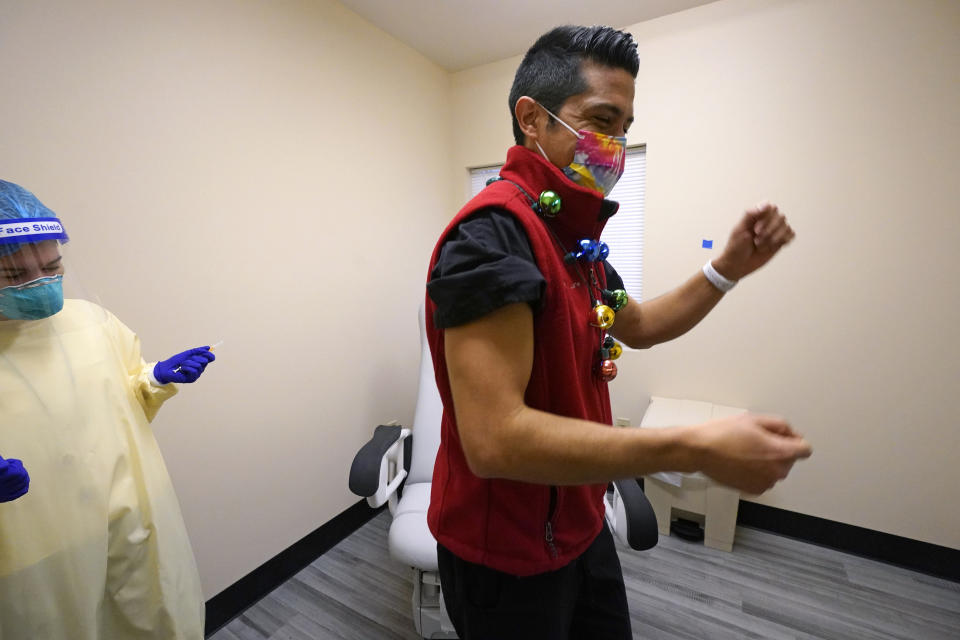 Dr. Dakotah Lane, a member of the Lummi Nation, right, does a brief dance after receiving a COVID-19 vaccination from registered nurse Alyssa Lane, Thursday, Dec. 17, 2020, at the Chinook Clinic on the Lummi Reservation, near Bellingham, Wash. The Native American tribe began rationing its first 300 doses of vaccine as it fights surging cases with a shelter-in-place order. (AP Photo/Elaine Thompson)