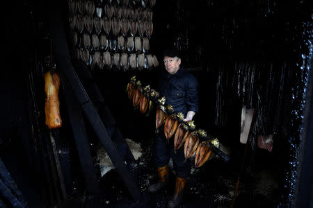 Derek Brown, 60, co-owner and 5th generation of Fortune's Kippers, who voted to leave the EU, holds some kippers in the smoking room of his family business that has been operating in the same building since 1872, in Whitby, Britain February 28, 2019. Brown pointed out that none of the fish he used were locally caught. For the past 30 years or so they have all been imported from Norway and Iceland. The smokers "defrost them overnight" he muttered, as if passing on a secret recipe. REUTERS/Clodagh Kilcoyne