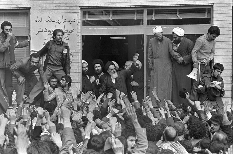 FILE - In this Feb. 1, 1979 file photo, Ayatollah Ruhollah Khomeini, center, waves to followers as he appears on the balcony of his headquarters in Tehran, Iran. Forty years ago, Iran's ruling shah left his nation for the last time and an Islamic Revolution overthrew the vestiges of his caretaker government. The effects of the 1979 revolution, including the takeover of the U.S. Embassy in Tehran and ensuing hostage crisis, reverberate through decades of tense relations between Iran and America. (AP Photo/Campion, File)
