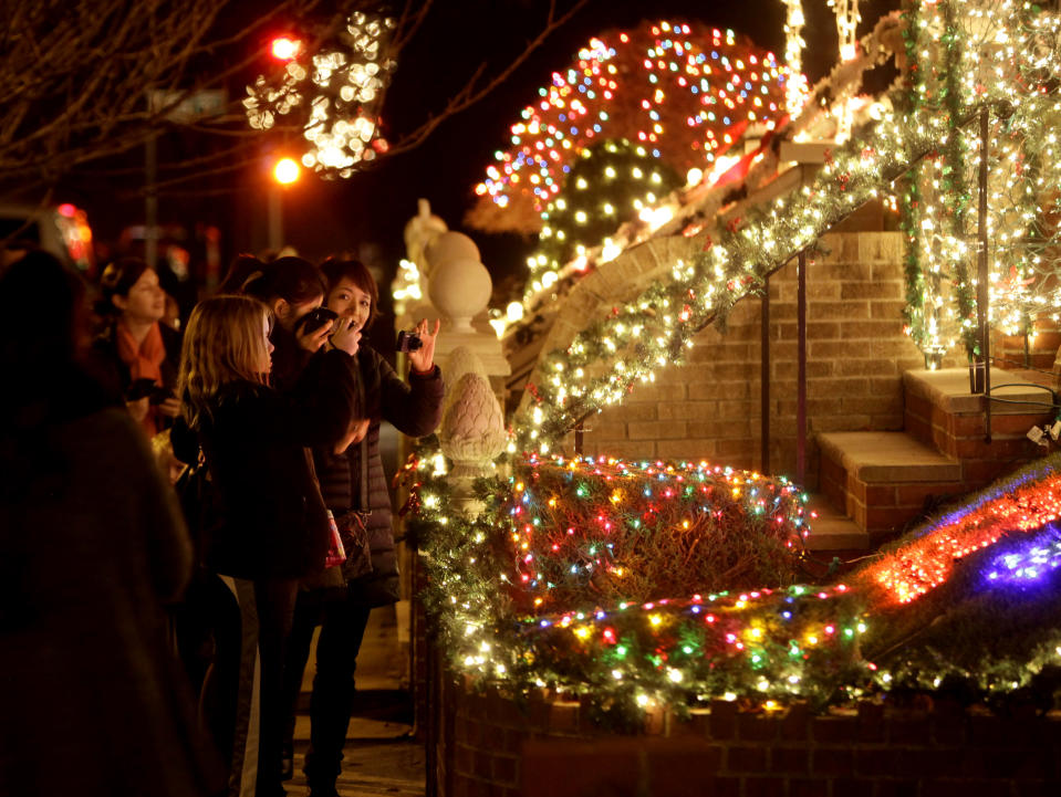 This Dec. 4, 2012 photo shows spectators viewing an elaborately decorated home for the holidays in the Brooklyn borough of New York. Each holiday season, tour operator Tony Muia takes tourists from around the world on his “Christmas Lights & Cannoli Tour” visiting the Brooklyn neighborhoods of Dyker Heights and Bay Ridge, where locals take pride in over-the-top holiday light displays. (AP Photo/Seth Wenig)