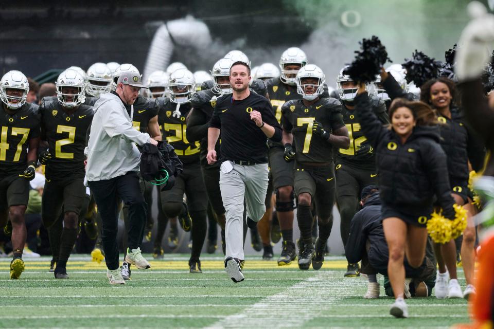 Oregon coach Dan Lanning runs out to the field with players before the team's game against California at Autzen Stadium.