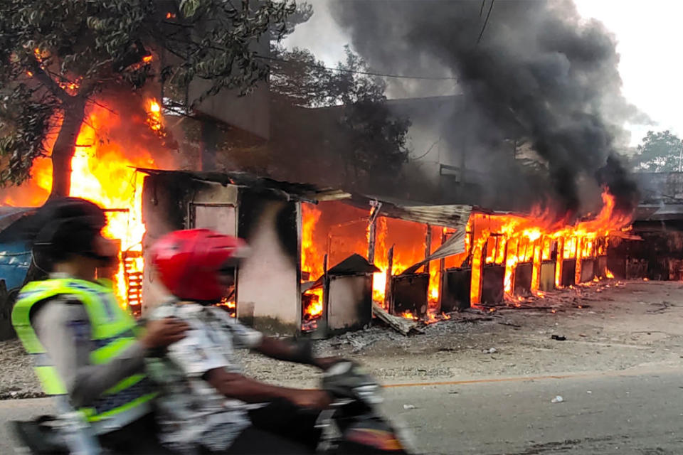 A motorist ride past a burning building after hundreds of demonstrators marched near Papua's biggest city Jayapura on August 29, 2019, where they set fire to a regional assembly building and hurled rocks at shops and hotels. Source: AFP