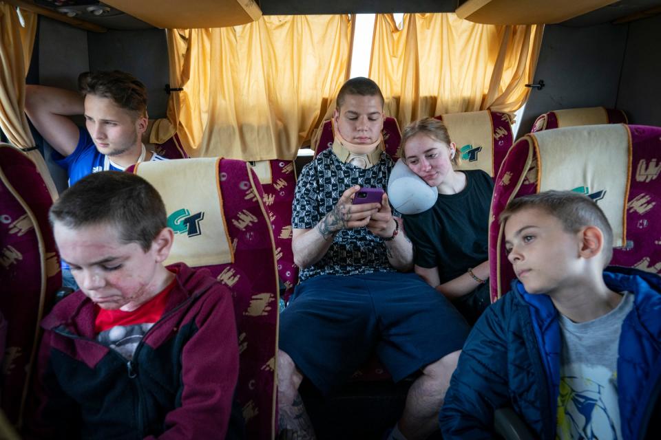 Artem Netreba, 12, left front, sits in the back of the bus with Danylo Tchaikovsky, left back, Egor Dikhtiaruk, 17, Mariia Ovdiienko, 16, and Oleksandr Leskiv, 9, on Saturday, May 20, 2023 as they travel with their families back to Ukraine after having surgeries in Poland. The teens made new friends after being brought together in Poland for their respective surgeries.