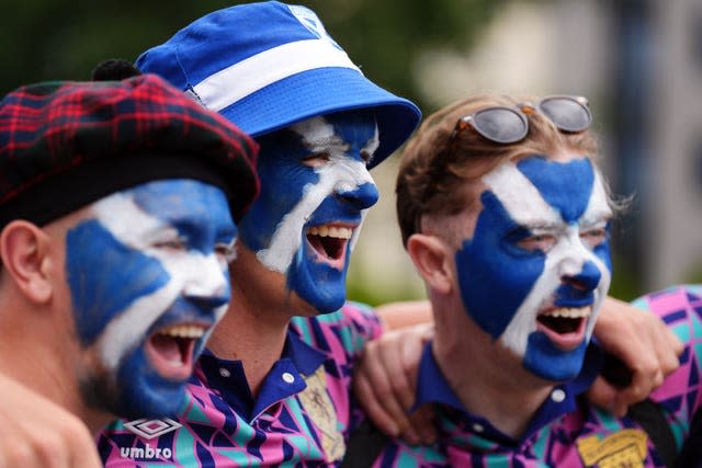 Three Scotland fans with their faces painted with the Saltire flag