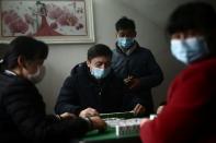 People wearing face masks play mahjong during home quarantine on the first day of the Chinese Lunar New Year of the Rat, at a village in Hubei
