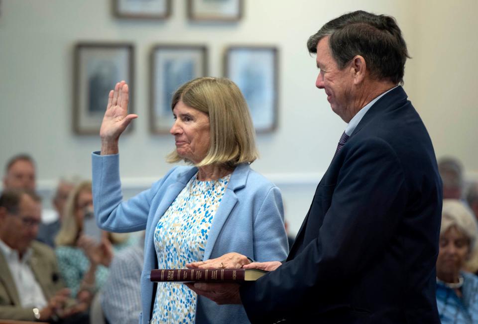 Town Council President Bobbie Lindsay takes the oath of office as her husband, Douglas Buck, holds the Bible during Tuesday's town council meeting..