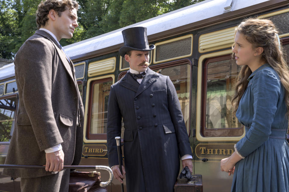 Sherlock and Mycroft talk to their sister by a train in Enola Holmes