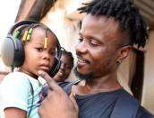 Yousef Kamara holds his daughter Stylvia in front of their house in Freetown,