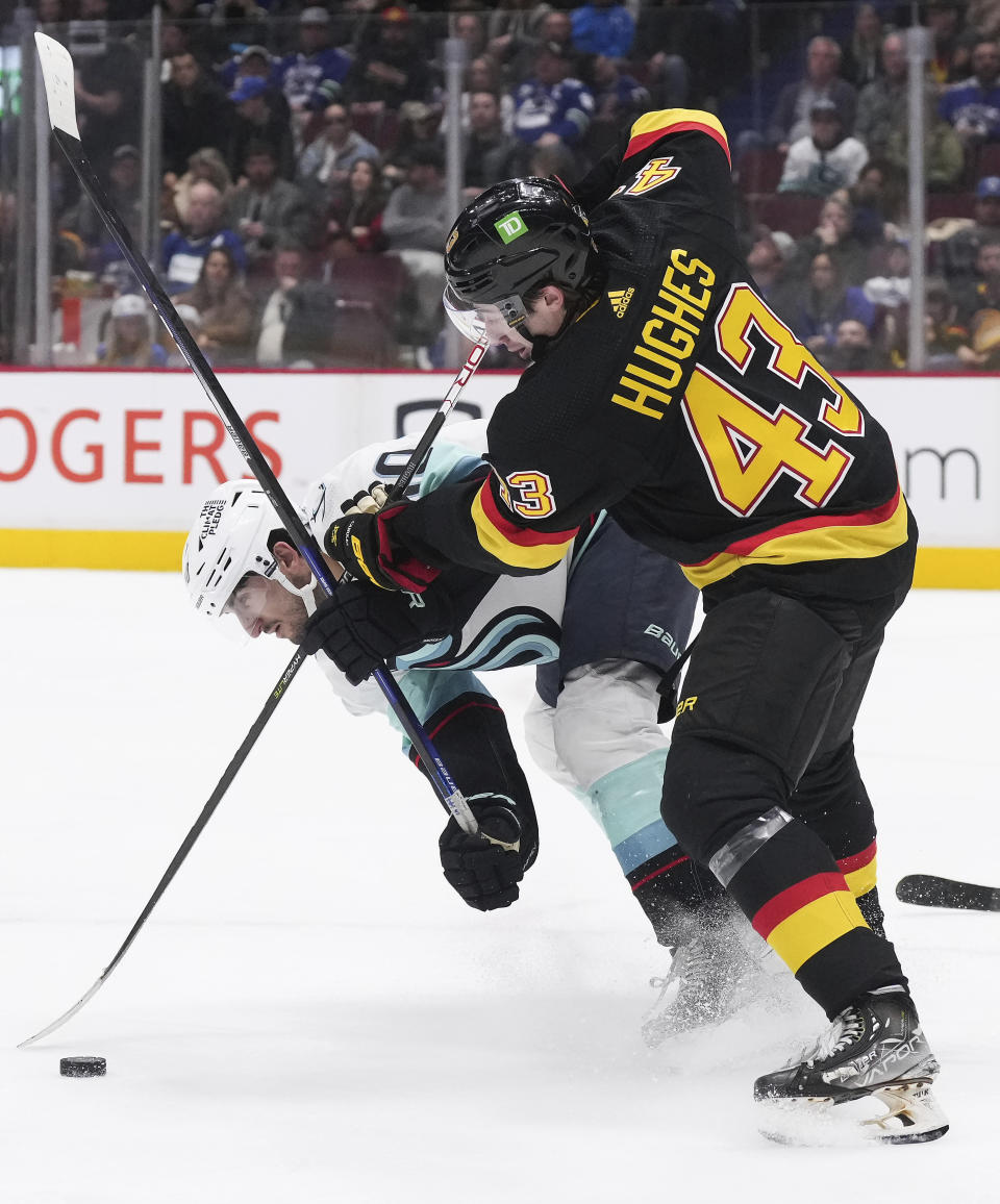 Vancouver Canucks' Quinn Hughes (43) checks Seattle Kraken's Matty Beniers (10) during the third period of an NHL hockey game Tuesday, April 26, 2022, in Vancouver, British Columbia. (Darryl Dyck/The Canadian Press via AP)