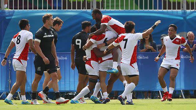 Japan celebrate after beating New Zealand 14-12 in their opening match of the Olympic rugby sevens. Source: Getty.