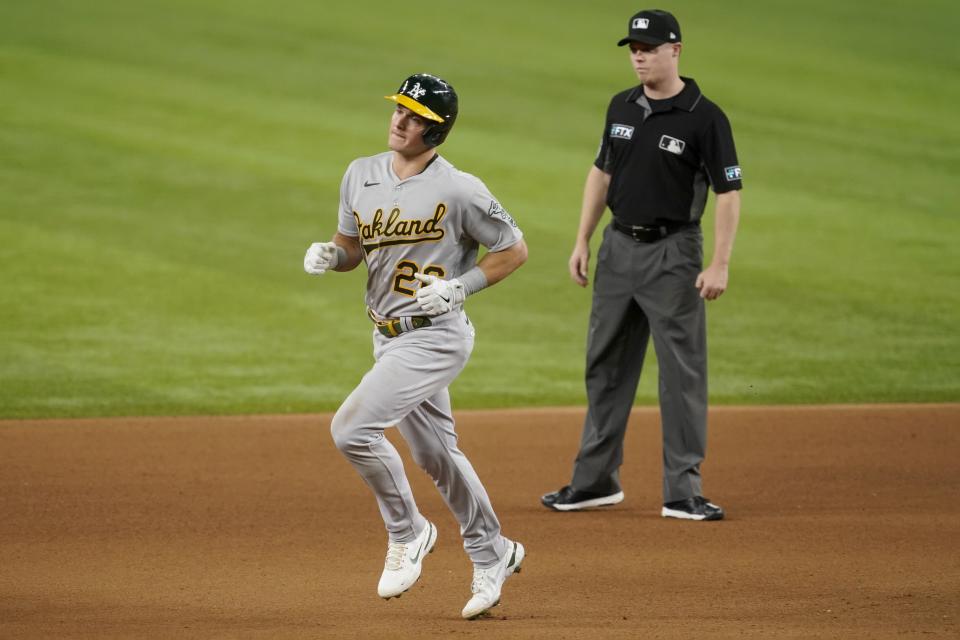 Oakland Athletics' Matt Chapman, left, rounds the bases past second base umpire Junior Valentine, rear, after hitting a solo home run in the seventh inning of the team's baseball game against the Texas Rangers in Arlington, Texas, Saturday, Aug. 14, 2021. (AP Photo/Tony Gutierrez)