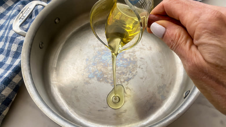 hand adding oil to pan