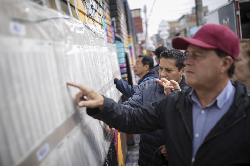 Voters look at lists during local and regional elections in Bogota, Colombia, Sunday, Oct. 29, 2023. (AP Photo/Ivan Valencia)