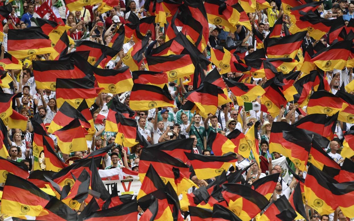 Germany's fans wave German national flags at an international football match - Patrik Stollarz/AFP