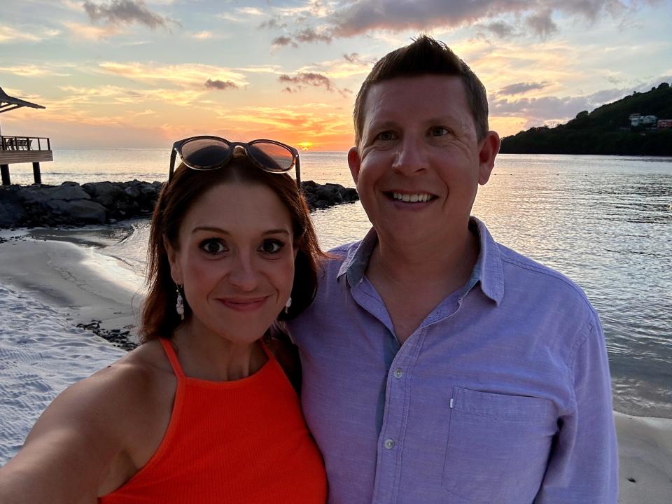 The author and her husband taking a selfie on a beach at sunset, both smiling.