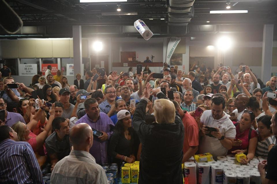 US President Donald Trump throws a paper towel roll as he visits the Cavalry Chapel in Guaynabo, Puerto Rico on October 3, 2017 (AFP via Getty Images)