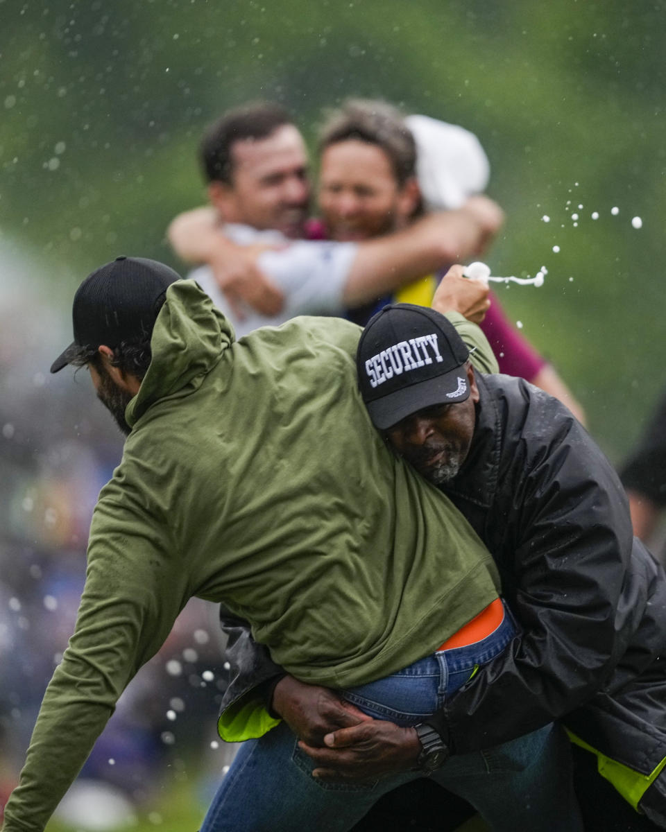 Canadian professional golfer Adam Hadwin, left, is stopped by a security guard while he tries to celebrates with Nick Taylor, of Canada, after Taylor won the Canadian Open golf tournament in Toronto, Sunday, June 11, 2023. (Andrew Lahodynskyj/The Canadian Press via AP)