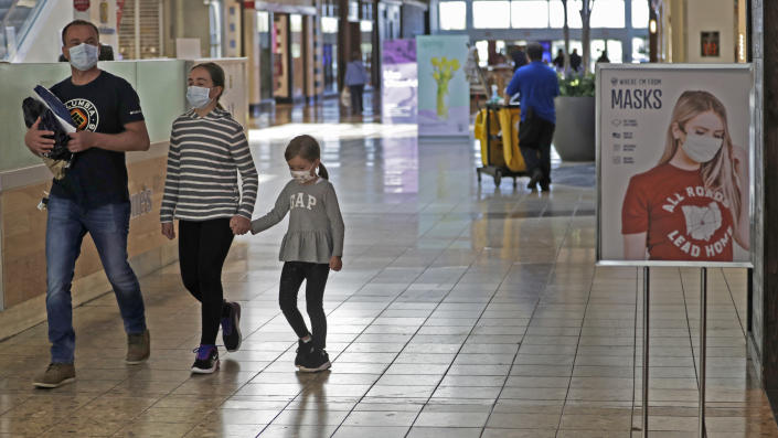 Shoppers walks past a sign encouraging masks at SouthPark Mall, Wednesday, May 13, 2020, in Strongsville, Ohio. Ohio retail businesses reopened Tuesday following a nearly two-month-long shutdown ordered by Gov. Mike DeWine to limit the spread of the coronavirus. (AP Photo/Tony Dejak)