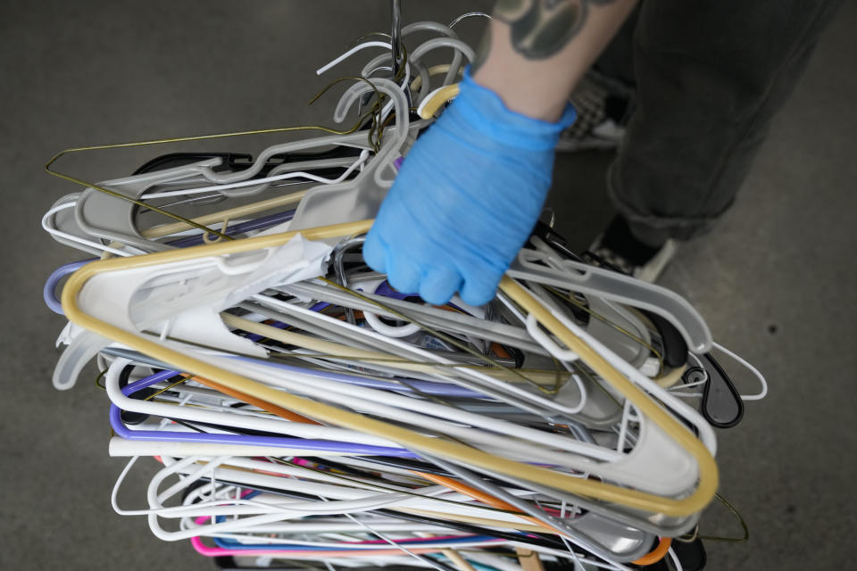 Michael Seid collects hangers after coats were given out at a donation center on Thursday, Jan. 11, 2024, in Portland, Ore. In just one hour, during Blanchet House's free lunch service, over 100 warm clothing items were claimed from the donation racks. Julie Showers, the nonprofit's communications director, said people were desperate for dry clothes and shoes after being soaked in days of cold rain. (AP Photo/Jenny Kane)