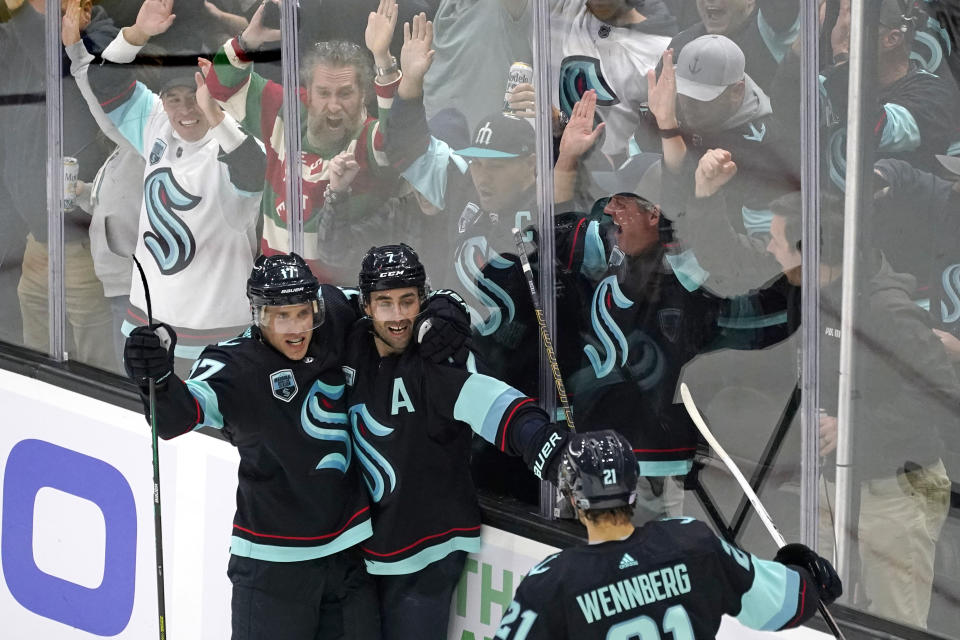 Fans cheer as Seattle Kraken's Jordan Eberle, center, is congratulated by teammates on his third goal of the night against the Buffalo Sabres,, during the third period of an NHL hockey game Thursday, Nov. 4, 2021, in Seattle. (AP Photo/Elaine Thompson)