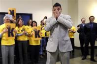 Seattle Mariners' Felix Hernandez covers his face as he is greeted by front-office staff all wearing yellow "Kings Court" T-shirts before a news conference, Wednesday, Feb. 13, 2013, in Seattle. Hernandez signed a seven-year contract with the Mariners that makes him the highest-paid pitcher in baseball. The new deal will be worth $175 million. (AP Photo/Elaine Thompson)