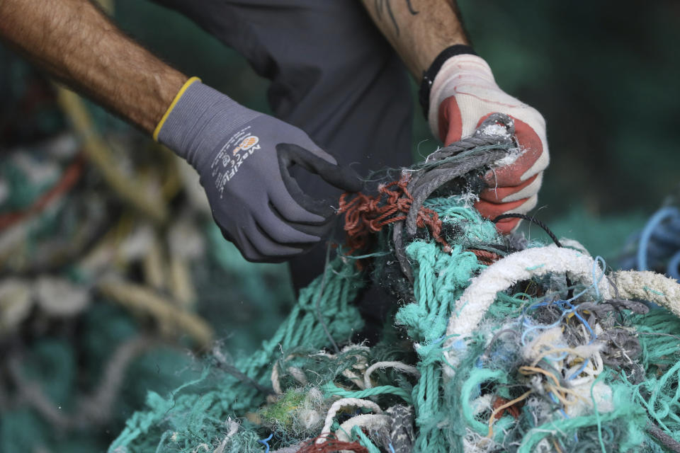 Drew McWhirter, a graduate student at Hawaii Pacific University's Center for Marine Debris Research, pulls apart a massive entanglement of ghost nets on Wednesday, May 12, 2021 in Kaneohe, Hawaii. Researchers are conducting a study that is attempting to trace derelict fishing gear that washes ashore in Hawaii back to the manufacturers and fisheries that it came from. (AP Photo/Caleb Jones)