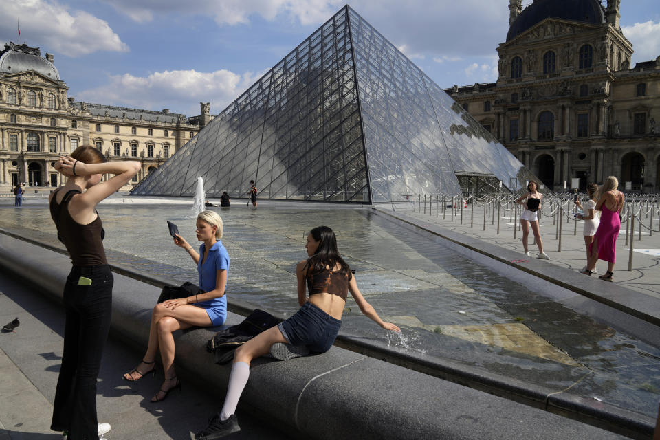 Visitors take a break outside the Louvre Museum courtyard, in Paris, Wednesday, June 9, 2021. France is back in business as a tourist destination after opening its borders Wednesday to foreign visitors who are inoculated against the coronavirus with vaccines approved by the European Union's medicines agency. France's acceptance of only the Pfizer, Moderna, AstraZeneca and Johnson & Johnson vaccines means that tourism is still barred for would-be visitors from China and other countries that use other vaccines. (AP Photo/Francois Mori)