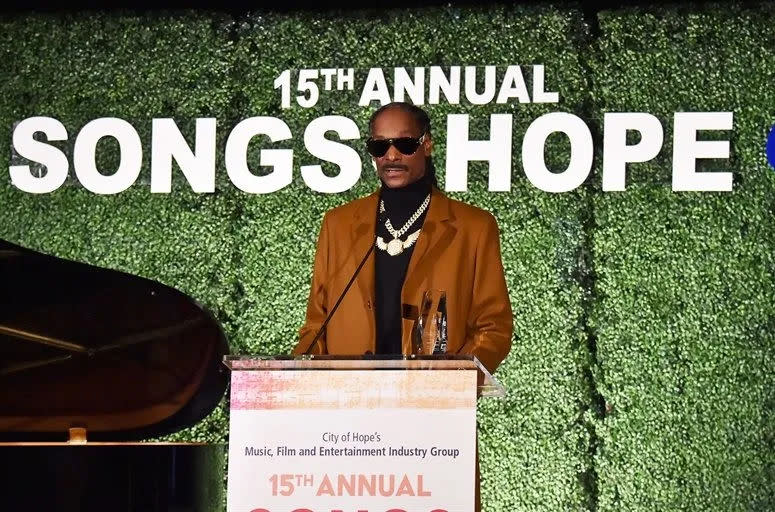 Rapper Snoop Dogg stands on a podium with the text 