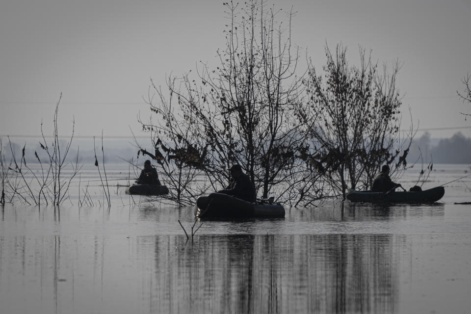 People fish in a flooded area in the village of Demydiv, about 40 kilometers (24 miles) north of Kyiv, Ukraine, Tuesday, Nov. 2, 2022. After the flood in Demydiv, residents said their tap water turned cloudy, tasted funny and left a film on pots and pans after cooking. The village was under Moscow's control until April, when Russian troops withdrew after failing to take the capital. (AP Photo/Andrew Kravchenko)