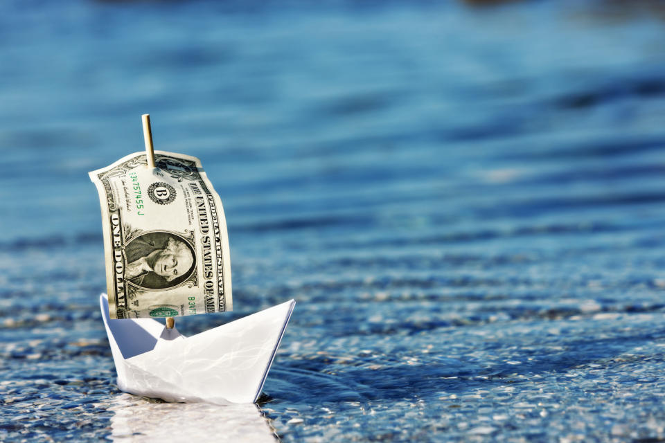 a paper boat with a dollar bill for a sail