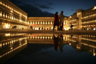 Locals and tourists walk along a nearly empty St. Mark's square in Venice, Italy, Tuesday, March 3, 2020. Venice in the time of coronavirus is a shell of itself, with empty piazzas, shuttered basilicas and gondoliers idling their days away. Venice, a UNESCO world heritage site, had already been brought to its knees last year, when near-record high tides flooded a lagoon city used to frequent spells of "aqua alta." (AP Photo/Francisco Seco)