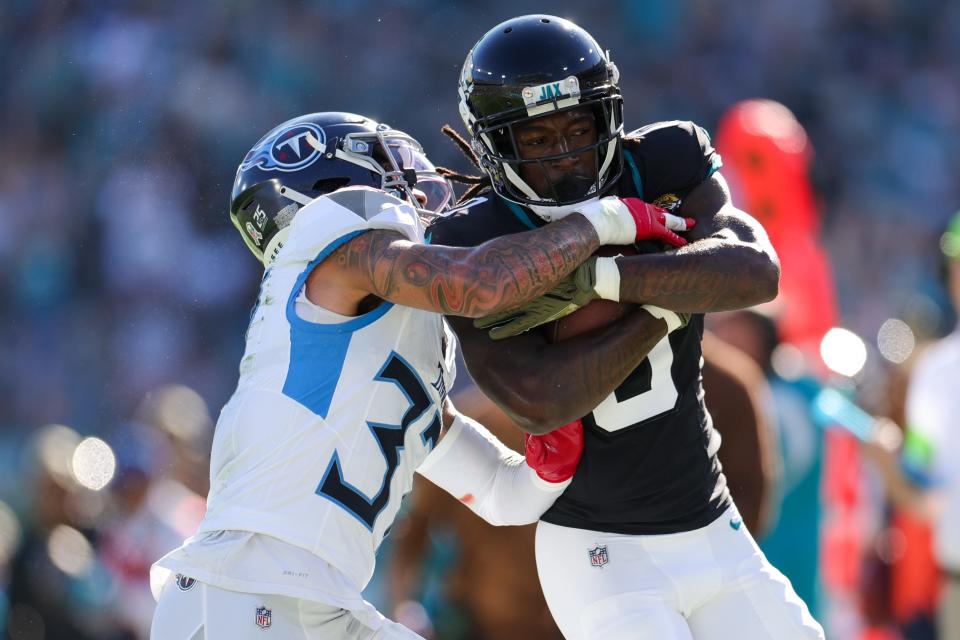 Tennessee Titans safety Amani Hooker (37) attempts to strip the ball from Jacksonville Jaguars wide receiver Calvin Ridley (0) in the second quarter at EverBank Stadium on Nov. 19, 2023 in Jacksonville, Florida.