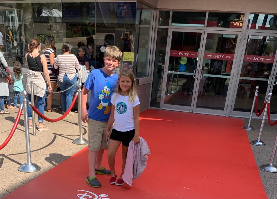 Terri Peters' kids outside of AMC Disney between ropes standing on a red carpet.