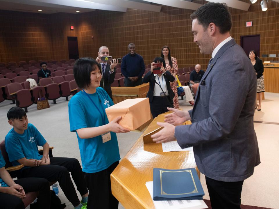 Japanese exchange student Mirei Kusakabe presents Pensacola Mayor D.C. reeves with a gift during the student visit to City hall on Wednesday, March 29, 2023.
