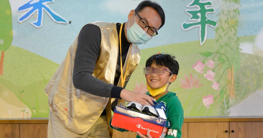 收到協會秘書長王愍之(左)代表致贈的運動鞋，小朋友露出開心的笑容。（圖／道家人文協會提供）