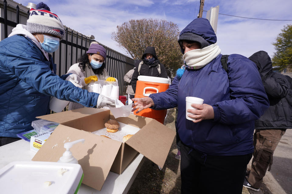 Members of the Templo De Celebration of Decatur hand out food and warm drink outside a warming center in Fort Worth, Texas, Friday, Dec. 23, 2022. (AP Photo/LM Otero)