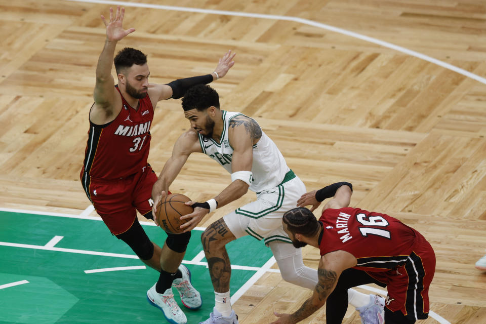 Boston Celtics forward Jayson Tatum drives to the basket between Miami Heat guard Max Strus (31) and forward Caleb Martin (16) in the first half of Game 1 of the NBA basketball Eastern Conference finals playoff series in Boston, Wednesday, May 17, 2023. (AP Photo/Michael Dwyer)