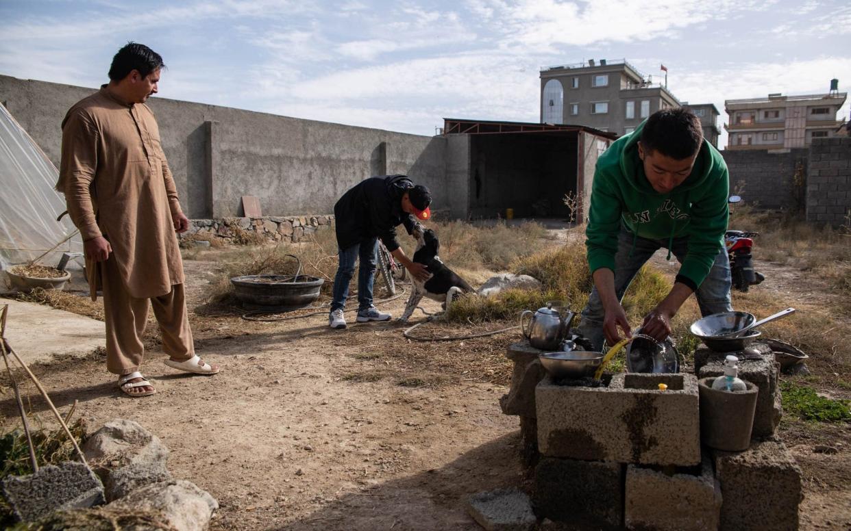 Nabi Eskandari washes dishes outside his small rented room - Stefanie Glinski