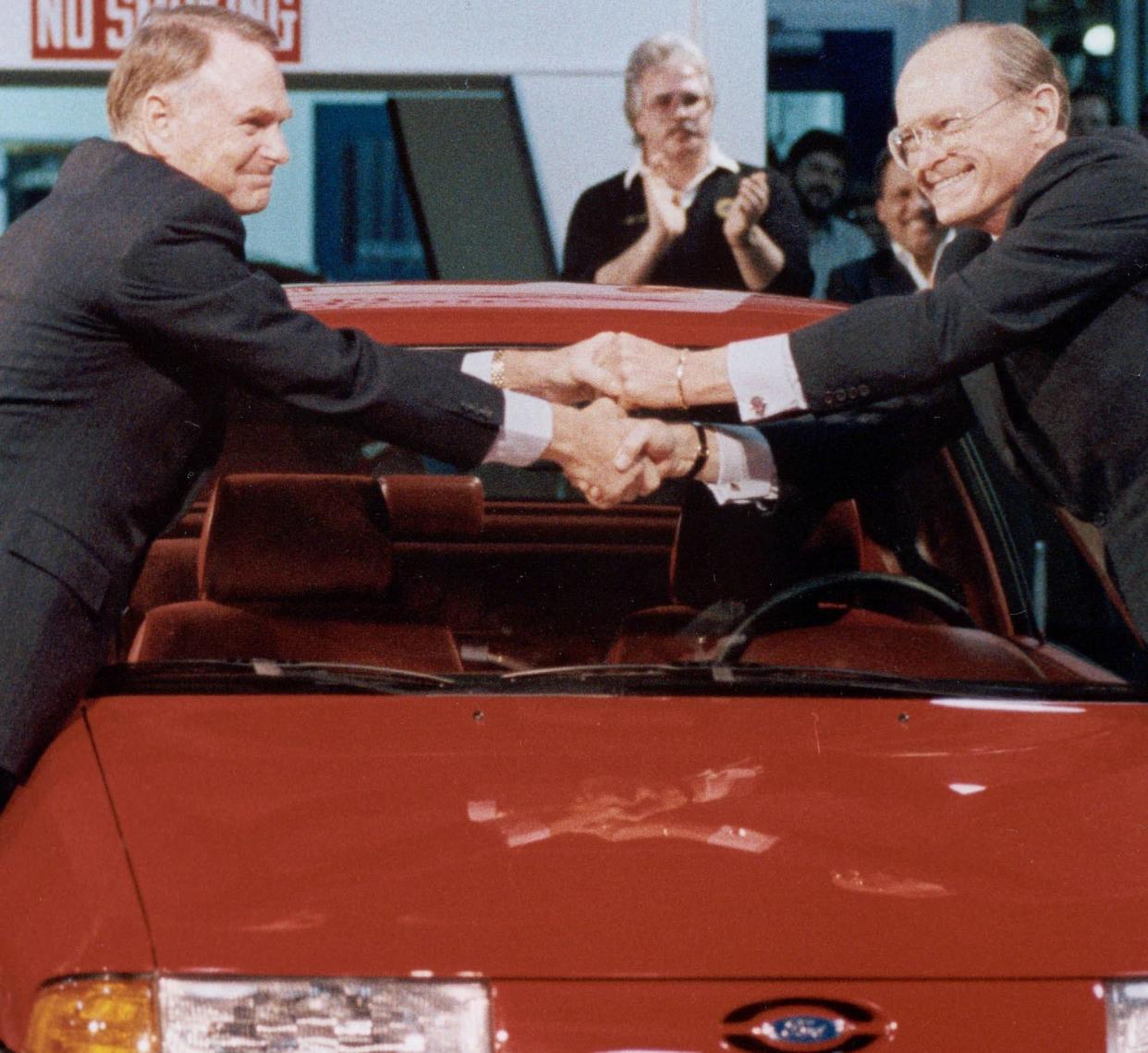 Harold Poling, left, shakes hands with Don Petersen. Poling succeeded Petersen as CEO at Ford Motor Co.