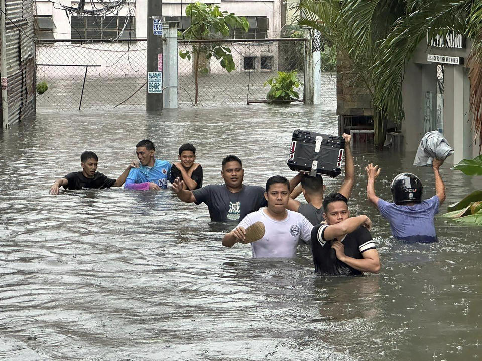 People wade through a flooded street following monsoon rains worsened by offshore typhoon Gaemi on Wednesday, July 24, 2024, in Manila, Philippines. (AP Photo/Joeal Capulitan)