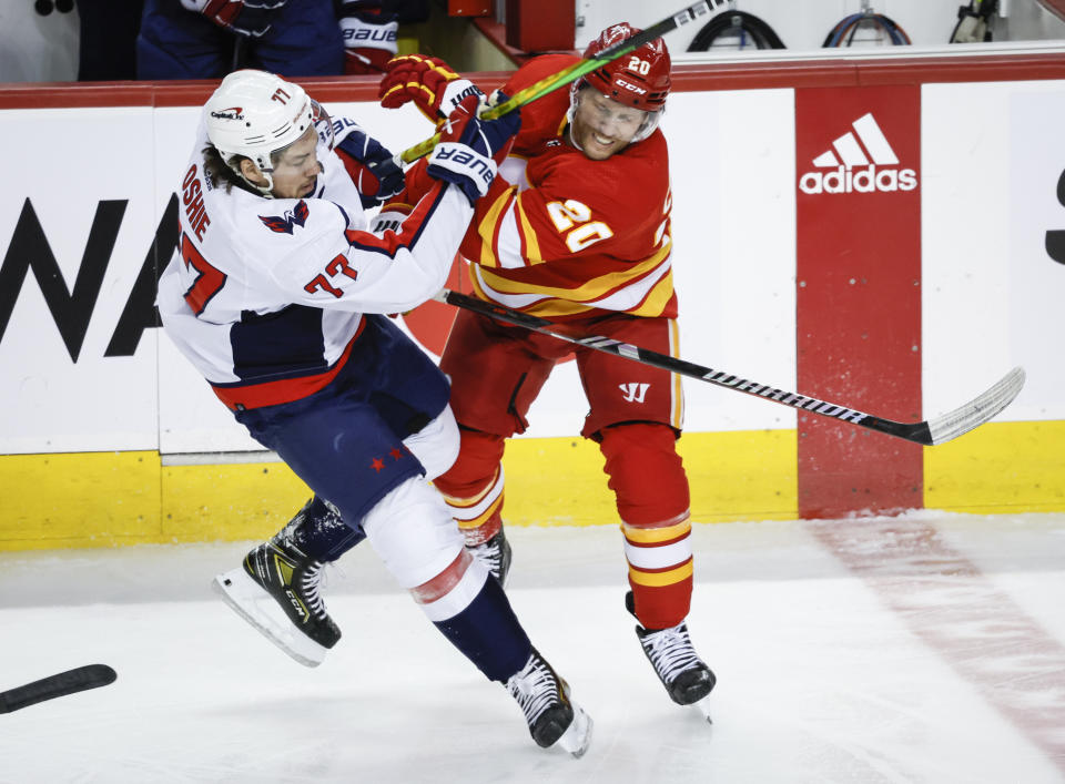 Washington Capitals forward T.J. Oshie (77) is checked by Calgary Flames forward Blake Coleman (20) during first-period NHL hockey game action in Calgary, Alberta, Monday, March 18, 2024. (Jeff McIntosh/The Canadian Press via AP)