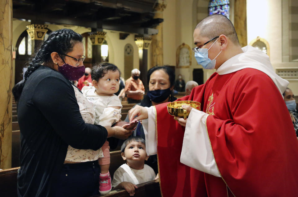 CORRECTS DATE TO JULY 6, 2020 INSTEAD OF JULY 7, 2020 - Parishioners receive the sacrament from the Rev. Luis Gabriel Medina during Communion at Saint Bartholomew Roman Catholic Church in the Queens borough of New York, Monday, July 6, 2020. This was the first in-person Mass at the church in almost four months. (AP Photo/Jessie Wardarski)